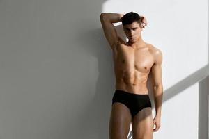 handsome man in black panties posing on a light background model photo