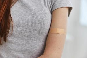 woman with adhesive plaster on shoulder vaccine passport immunity health photo