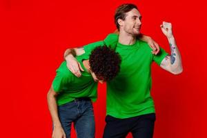 funny friends green t-shirts hugs emotions joy red background photo