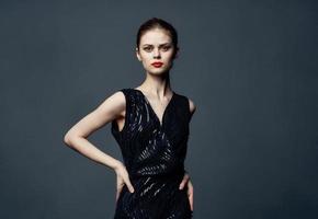 Charming lady in a black dress with bare shoulders on a gray background Copy Space photo