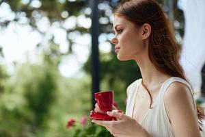 bonito mujer participación un café taza en pie en el parque a verano verano día foto