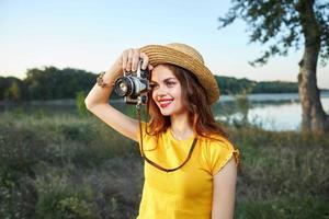 mujer fotógrafo mira dentro el cámara lente sonrisa rojo labios Fresco aire naturaleza pasatiempo foto