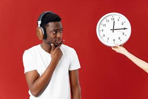man in white t-shirt wearing headphones looks at the clock music photo