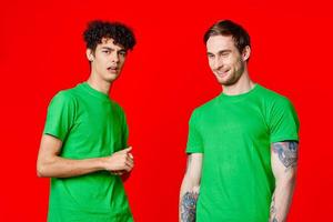 alegre amigos en verde camisetas sostener en a el cara de emoción foto