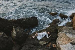 woman lying on rocky coast with cracks on rocky surface vacation concept photo