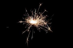Burning sparkler isolated on black background. Fireworks theme. Light effect and texture. photo