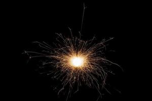 Burning sparkler isolated on black background. Fireworks theme. Light effect and texture. photo