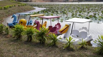 Attractions colorful paddle wheeler pedal boat ducks parking at the side lake. photo