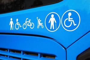 Disabled sign, elderly people, baby carriage and bicycle icons on city bus. Public transportation accessibility concept photo