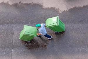 garbage man at work moving trash containers, top view photo