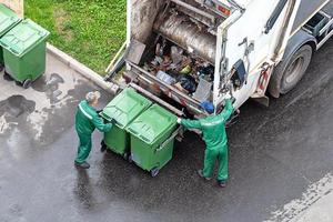 dos trabajadores cargando mezclado Doméstico residuos en residuos colección camión foto