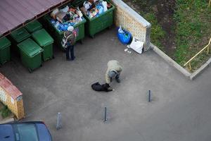 personas excavación en contenedores de basura y alimentación su perro, Moscú, 28.10.2019 foto