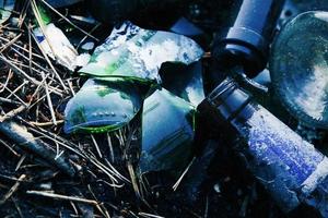 Broken glass bottles left in the forest, environmental pollution problem photo