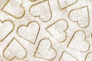 Background of ginger dough with cut heart shaped cookies, sprinkled with flour photo