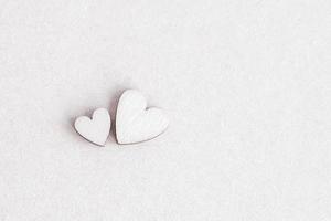 un par de corazones de madera blanca sobre fondo beige claro, espacio de copia foto