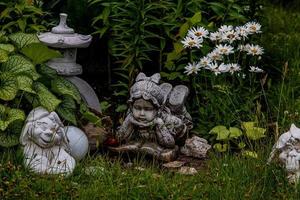 green garden with flowers and plaster figurine natural background photo