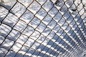 metal mesh, fence on white snow background in winter day in close-up photo