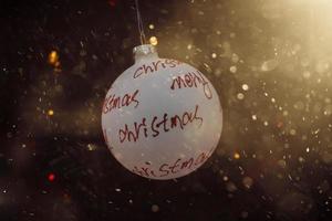 white bauble with red inscription merry christmas on a festive background photo