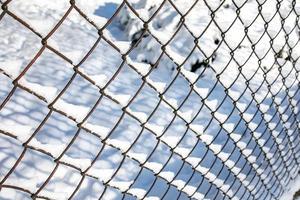 metal mesh, fence on white snow background in winter day in close-up photo