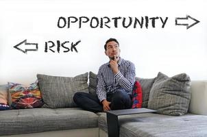 Man contemplating on couch, trying to decide between Risk and Opportunity photo