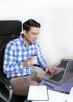 A man in a checked shirt working from home at a desk photo