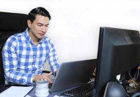 un hombre en un comprobado camisa trabajando desde hogar a un escritorio foto