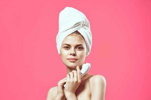 woman with bare shoulders facial massage clear skin pink background photo