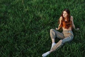 A girl sits on the grass in the park and enjoys the beautiful view of the summer sunset photo