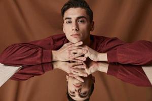 Handsome guy and brown shirt leaned on the glass on a fabric background photo