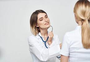 A nurse doctor in a medical gown explains something to a patient in a white T-shirt photo