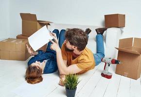 happy man and woman lie on the floor a flower in a pot planning future renovation work photo