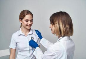 médico mujer con un estetoscopio sostiene un paciente por el hombro en un ligero antecedentes foto