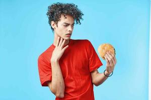 guy with curly hair in red t-shirt hamburger fast food blue background photo