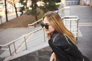 Stylish woman in a leather jacket and glasses on the street in the city model photo