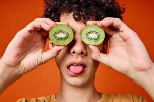 Cheerful man with curly hair kiwi fruit fun red background photo