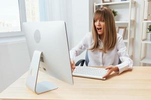 Shocked excited blonde businesswoman hold keyboard confused after computer software crash error at workplace in modern office. Upset director work online in financial corporation. Copy space photo