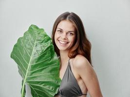 smiling woman in gray swimsuit and green leaf exotic cropped view photo