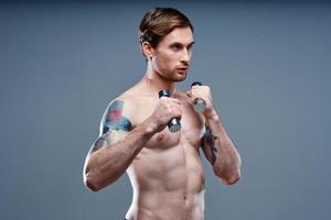 guy with a pumped up torso and with dumbbells on a gray background cropped view of the press and biceps fitness photo