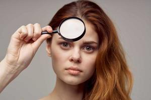 beautiful woman magnifier near the face hygiene close-up photo