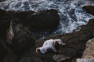 woman in a white dress lying on a stone in a white dress unaltered photo