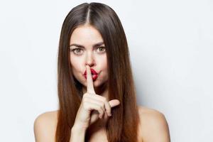 Girl holds his finger to his lips, top secret bare shoulders attractive look isolated background Copy space photo