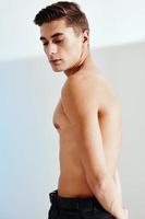 Handsome guy with a naked torso and in black trousers portrait back view photo