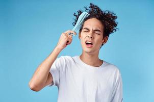 indignant guy combing hair with blue comb on isolated background cropped view photo