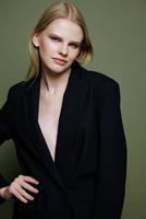 Attractive beautiful bright girl smiling looks into the camera posing in the studio in a suit on a green background photo