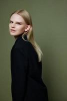 Attractive beautiful bright girl looks into the camera posing in the studio in a suit on a green background photo