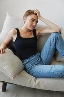 Young woman with short haircut hair having fun at home on the couch smile and happiness, vacation at home, natural posing without filters, free copy space photo