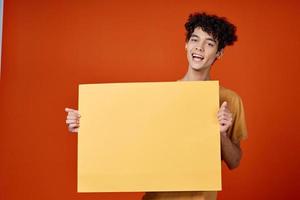 guy with curly hair yellow poster in hands studio advertising photo