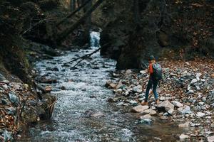 mujer caminante con un mochila en el río banco y el bosque en el distancia alto arboles foto