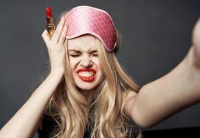 Drunk woman with lipstick on a gray background gestures with her hands photo