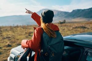 woman near cars gesturing with her hands on nature in the mountains autumn backpack travel tourism photo